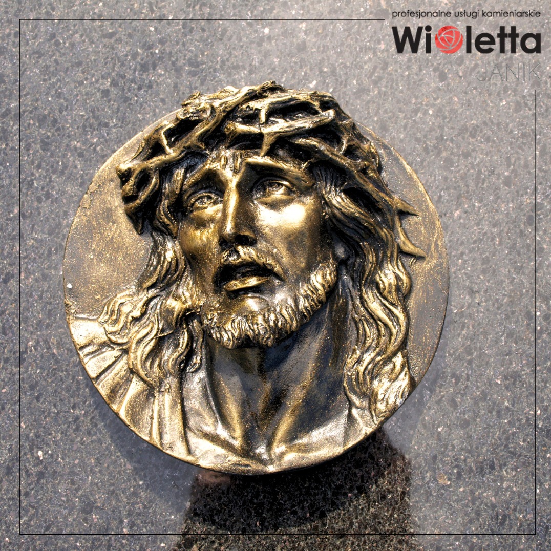 Medalion nagrobny – wizerunek Chrystusa – rzeźba z brązu, podkreślająca religijny charakter pomnika.