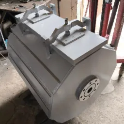 Szary, spawany walec z metalu z przymocowanymi uchwytami, umieszczony na palecie widłowej w warsztacie.