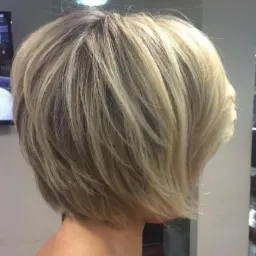 Krótka, warstwowa fryzura z blond pasemkami, widok z profilu, oświetlenie studyjne.