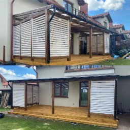 Zadaszony taras z drewnianą podłogą i białymi, poziomymi żaluzjami na ścianach bocznych, widok z zewnątrz, brązowe drewno konstrukcyjne, dom w tle.