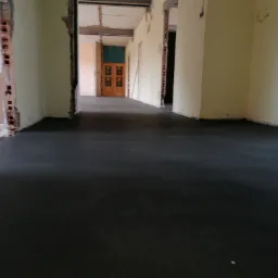 Świeżo wylana, ciemnoszara posadzka w trakcie remontu mieszkania, z widocznymi śladami prac murarskich na ścianach i otwartymi przejściami do kolejnych pomieszczeń.