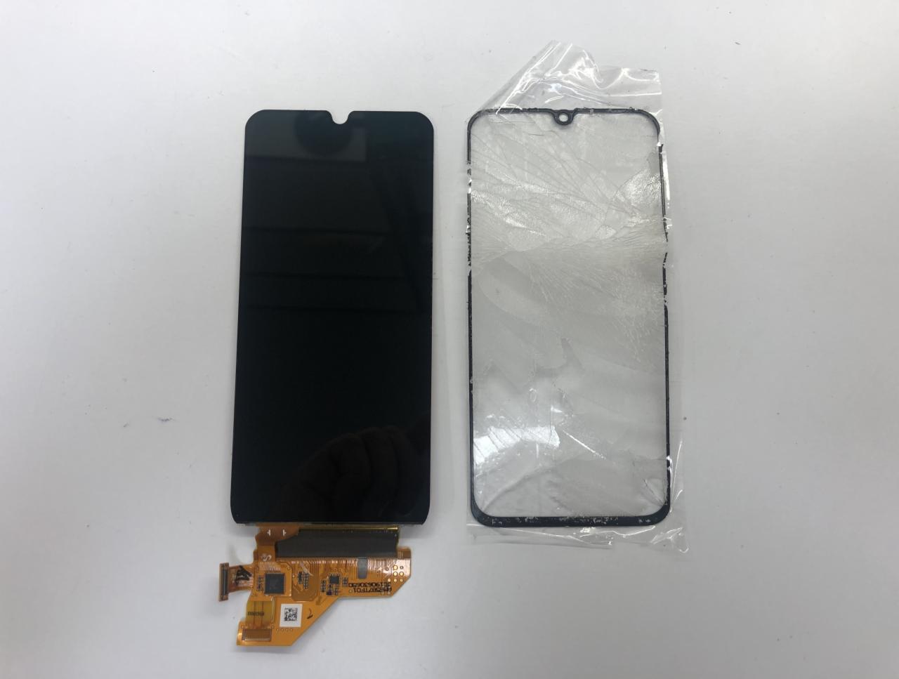 Ekran telefonu z taśmą flex i pęknięta szybka w folii ochronnej leżą obok siebie na białym tle.