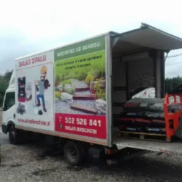 Ciężarówka Składu Opału 'Wszystko do Ogrodu' z otwartą paką załadowaną workami ekogroszku na palecie, gotowa do rozładunku za pomocą czerwonego wózka widłowego