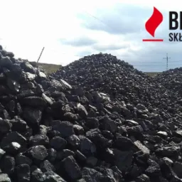 Skladowisko węgla kamiennego z logo firmy Bento Skład Opału w prawym górnym rogu, widoczne trzy pryzmy węgla na betonowym placu pod pochmurnym niebem.