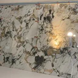 Montaż płytek imitujących marmur na ścianie w Zielonej Górze, widoczne poziomice laserowe i klipsy poziomujące.