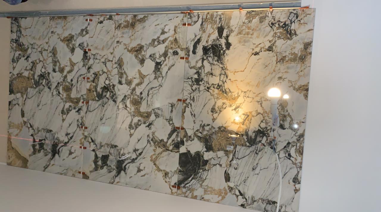 Montaż płytek imitujących marmur na ścianie w Zielonej Górze, widoczne poziomice laserowe i klipsy poziomujące.