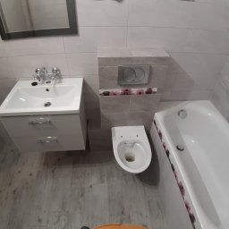 M.S KaFelki - Jasna łazienka po remoncie: umywalka z szafką, toaleta i wanna z kwiatowym motywem dekoracyjnym na kafelkach.