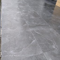 M.S KaFelki - Ułożona szara, kamieniopodobna terakota na podłodze balkonu, widoczne fugi i fragment ściany z oknem.