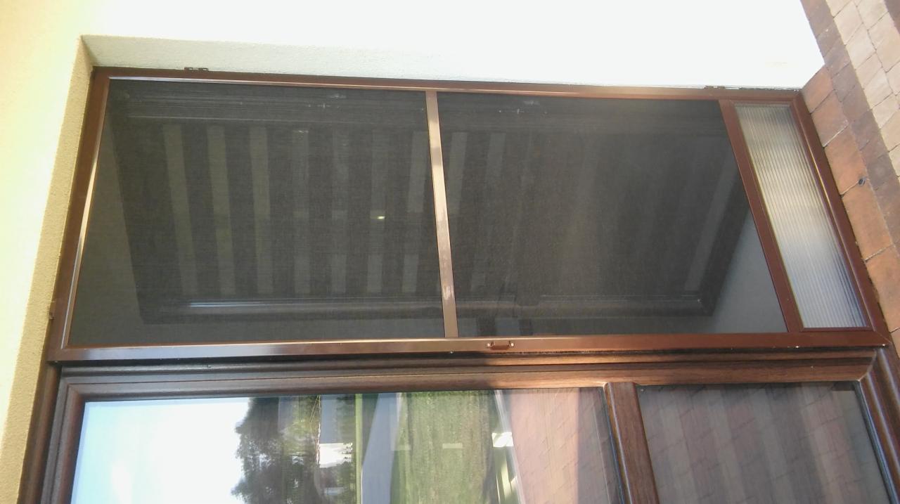 Zewnętrzna przesłona okienna z brązową ramą, widoczna od wewnątrz, z refleksami otoczenia w Pułtusku.