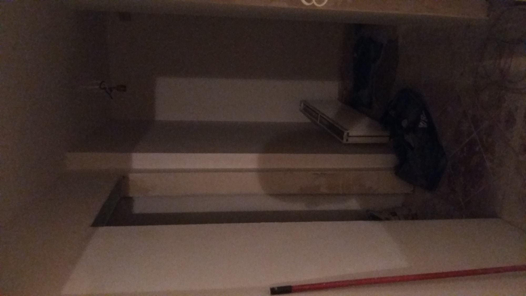 Wnętrze w trakcie prac, widoczne fragmenty ścian z położoną gładzią, częściowo zakryte narzędzia i akcesoria malarskie, czerwony ołówek na podłodze.