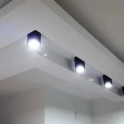 Biały sufit podwieszany z wbudowanymi, czarnymi reflektorami LED, tworzący geometryczny wzór oświetleniowy.