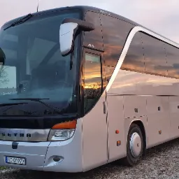 Autokar marki Setra S 417 HDH z polską tablicą rejestracyjną, zaparkowany na żwirowym podłożu, z odbijającym się zachodem słońca w oknach.