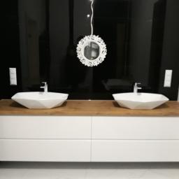 Kristol - Łazienka z dwoma umywalkami o geometrycznym kształcie, na drewnianym blacie i białej szafce, na tle czarnych płytek i ozdobnego lustra.