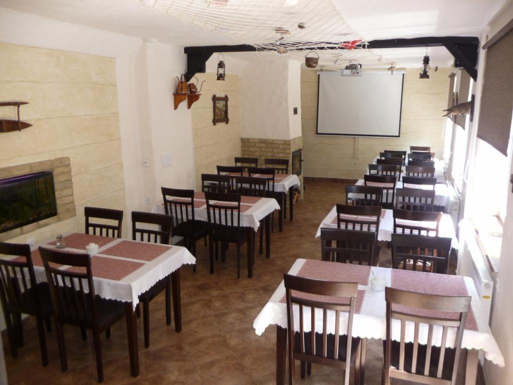 Sala restauracyjna w Szałem przygotowana na przyjęcie gości, z nakrytymi stołami, dekoracjami w stylu marynistycznym i ekranem projekcyjnym.