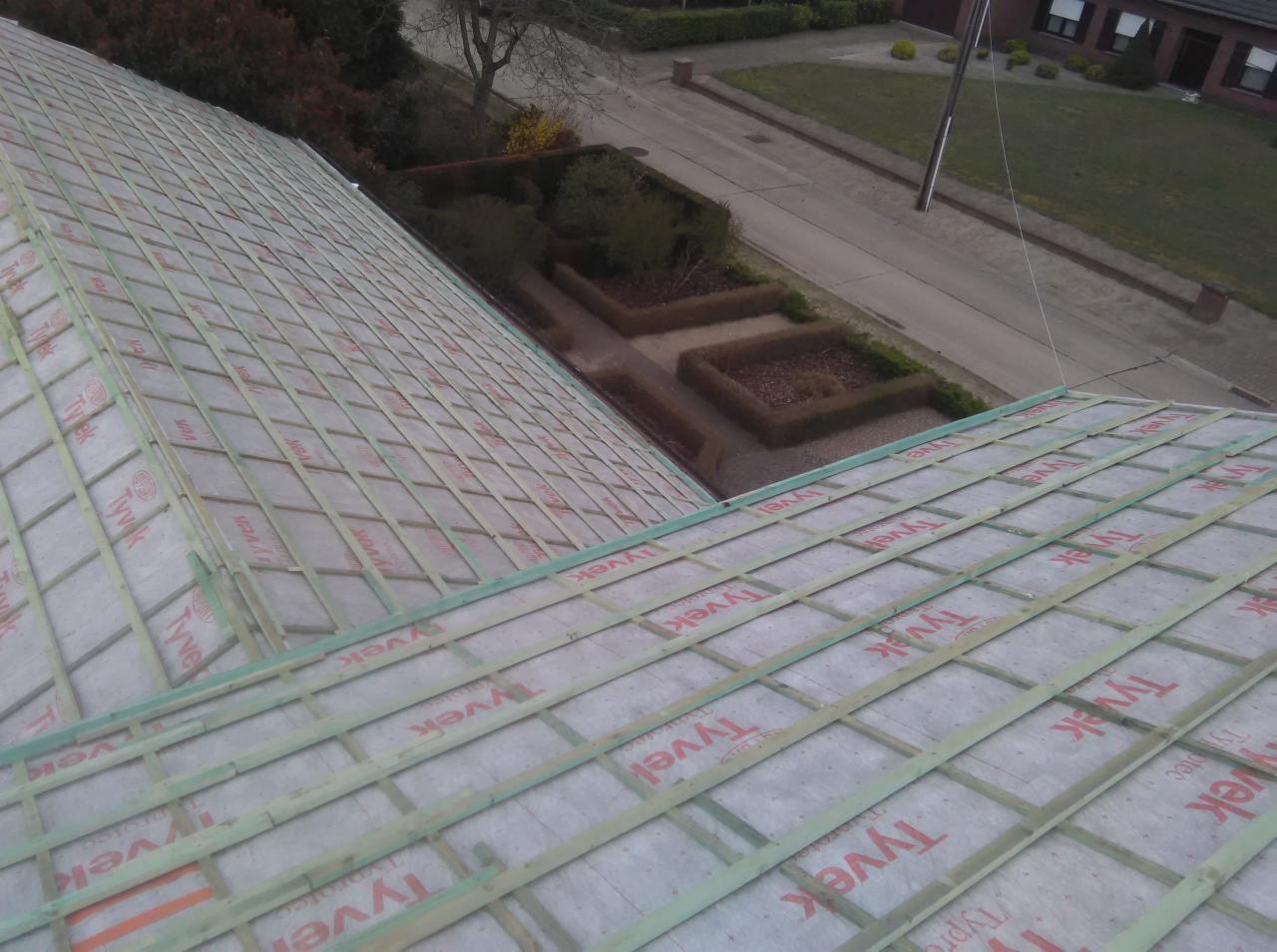 Konstrukcja dachu z drewnianych łat pokrytych membraną Tyvek, widok z góry na tle zieleni i ulicy.