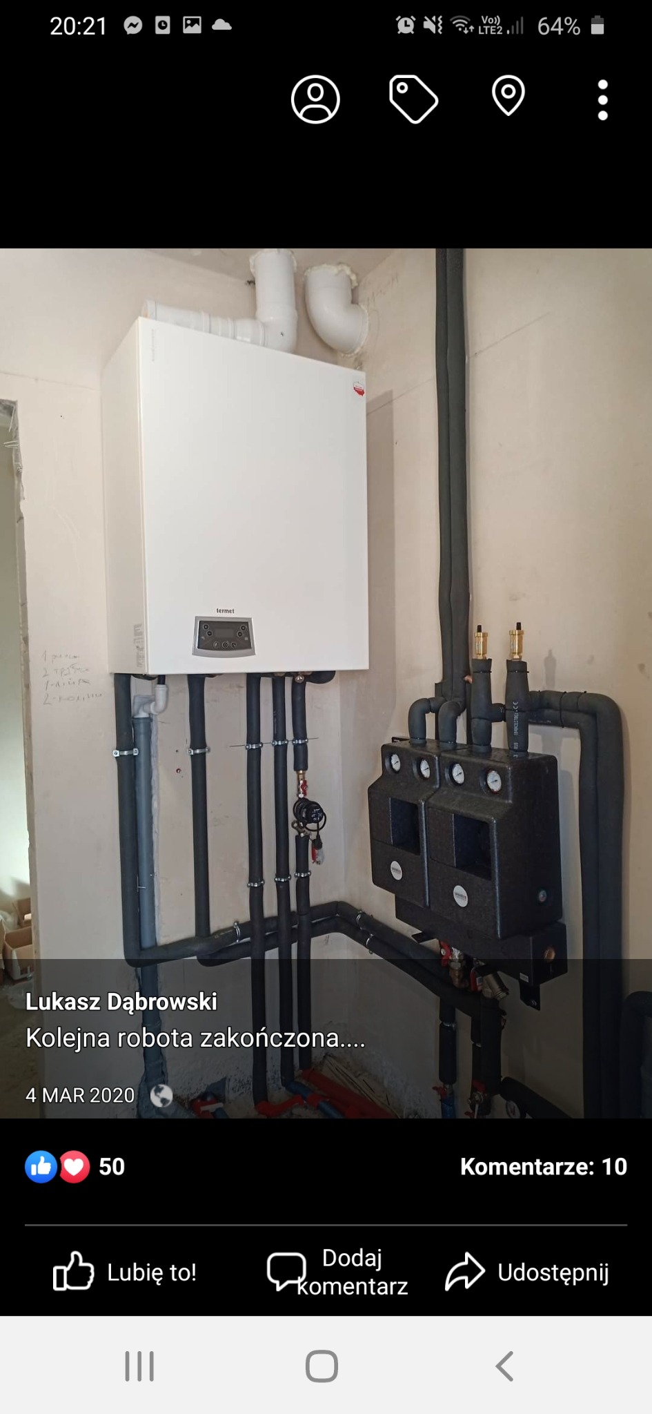 Biały piec gazowy marki Termet, zamontowany na ścianie z widocznymi rurami i czarną skrzynką rozdzielczą, instalacja grzewcza w trakcie podłączenia.