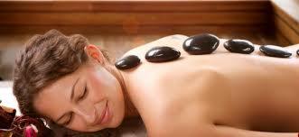 Kobieta leżąca na brzuchu z rozłożonymi gorącymi kamieniami na plecach podczas masażu relaksacyjnego w spa.