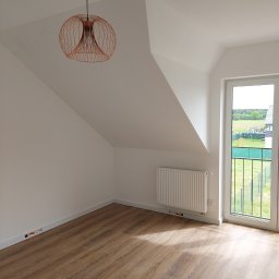 Lemkaz - Poddasze z oknem balkonowym, panelami podłogowymi i miedzianą lampą drucianą w stylu retro