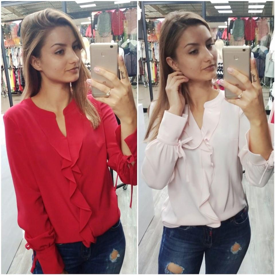 Selfie w lustrze prezentujące dwie bluzki z falbanami: czerwona i pudrowo-różowa, z rękawami zakończonymi wiązaniem, na tle wieszaków z ubraniami.