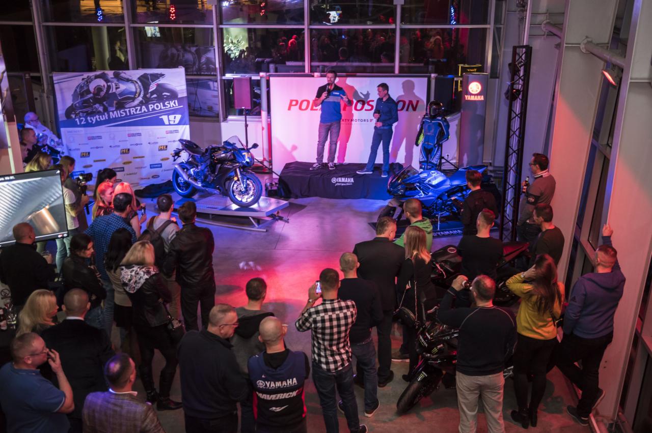 Prezentacja motocykli Yamaha na scenie podczas eventu, publiczność obserwuje dwóch prelegentów z mikrofonami, w tle baner z napisem '12 tytuł Mistrza Polski'.