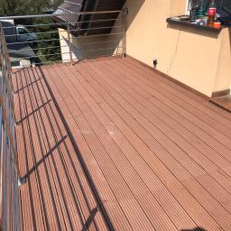 Glaz- Bud - Nowoczesny taras z desek kompozytowych w odcieniach brązu, z balustradą ze stali nierdzewnej, widok z góry na ukończoną realizację.