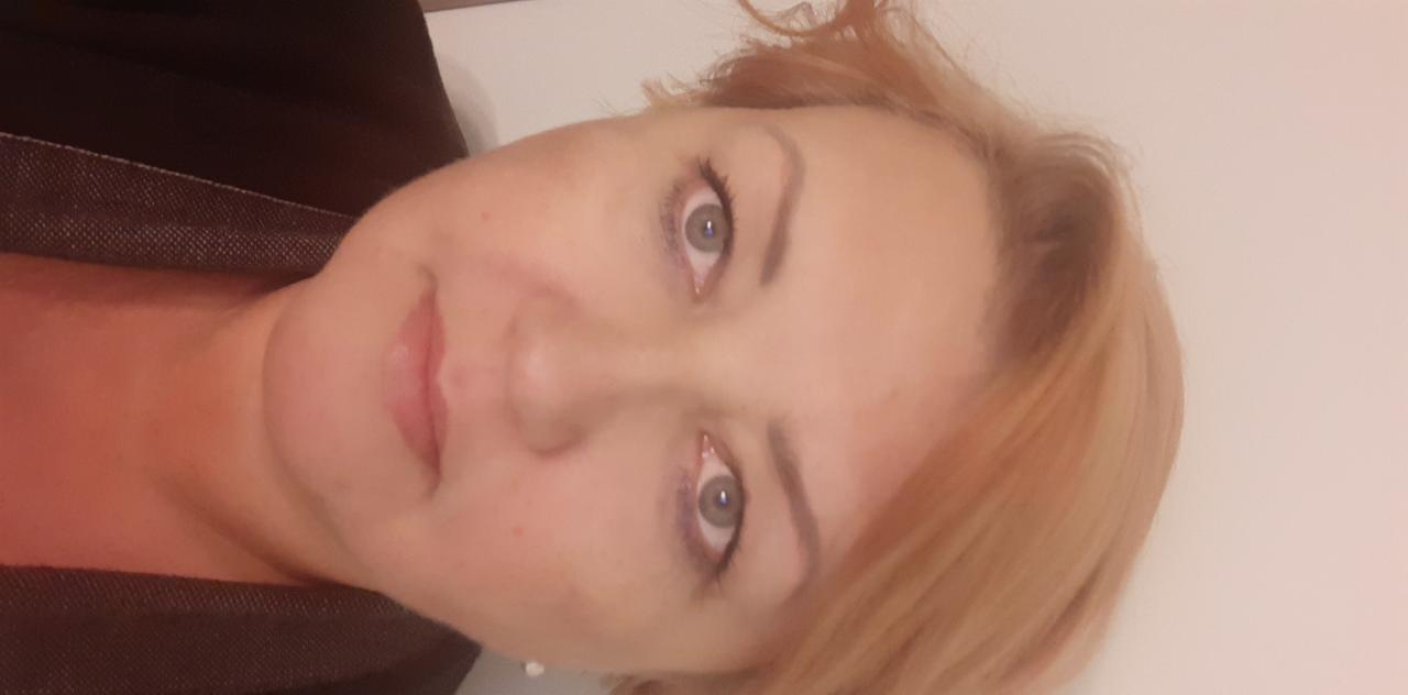 Portret kobiety z jasnymi włosami, skierowanej w lewo, z widocznymi zmarszczkami wokół oczu i ust, na jasnym tle.