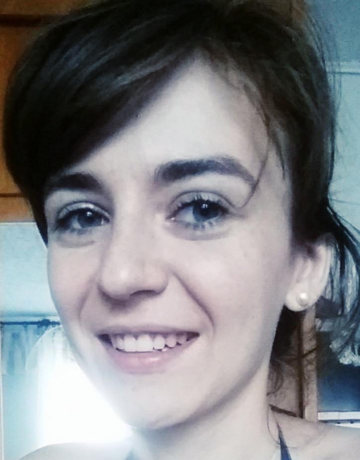 Portret uśmiechniętej młodej kobiety z krótkimi ciemnymi włosami i jasnymi oczami, noszącej perłowy kolczyk.