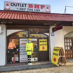 Fasada sklepu Outlet BHP z manekinami w odzieży roboczej w oknie wystawowym i tablicami informacyjnymi o wejściu.