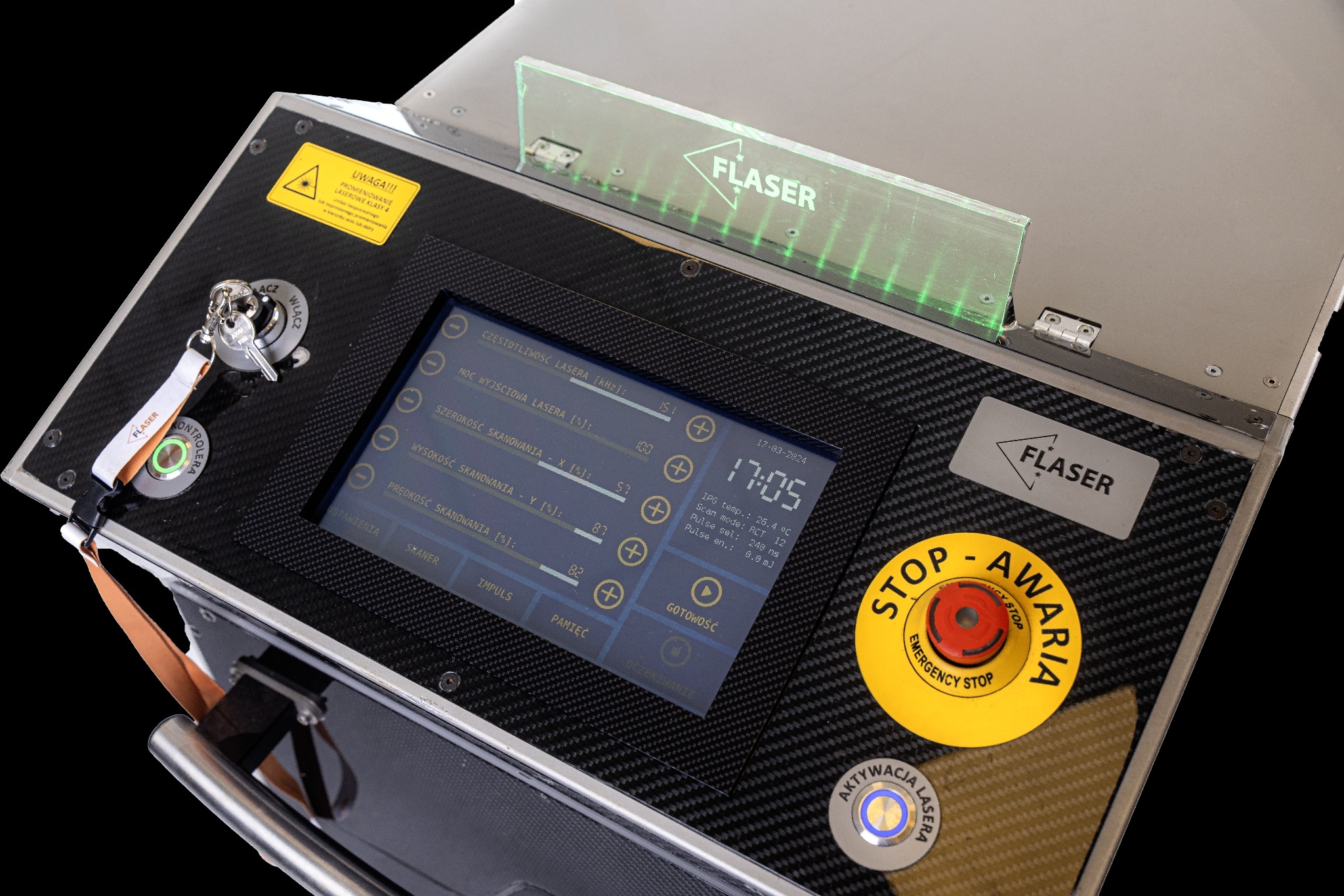 Panel sterowania urządzenia laserowego FLASER z widocznym ekranem dotykowym, przyciskiem awaryjnym i kluczykiem w stacyjce, na tle czarnego tła.
