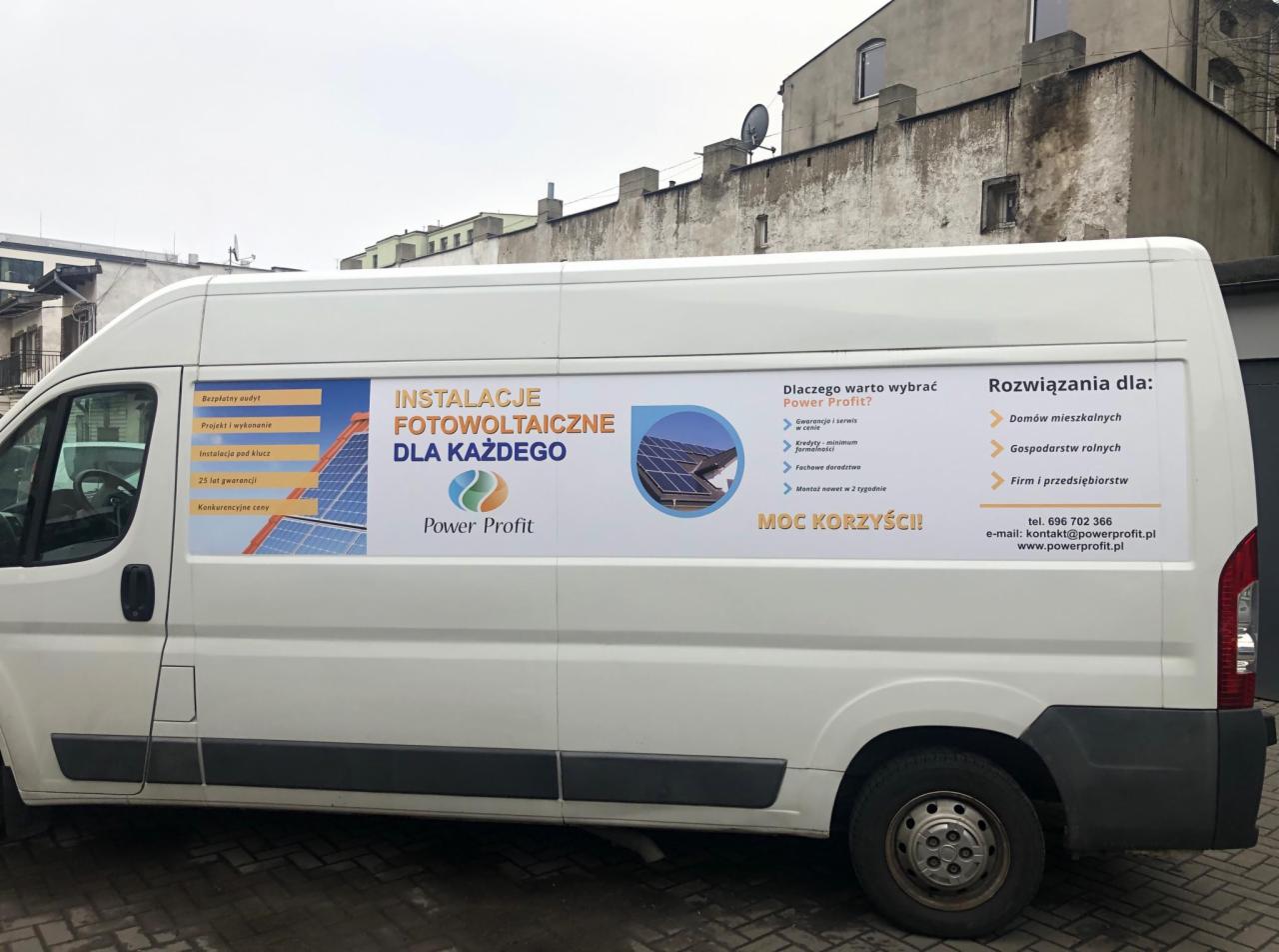 Biały samochód dostawczy z reklamą instalacji fotowoltaicznych firmy Power Profit, zaparkowany na tle miejskiego budynku.