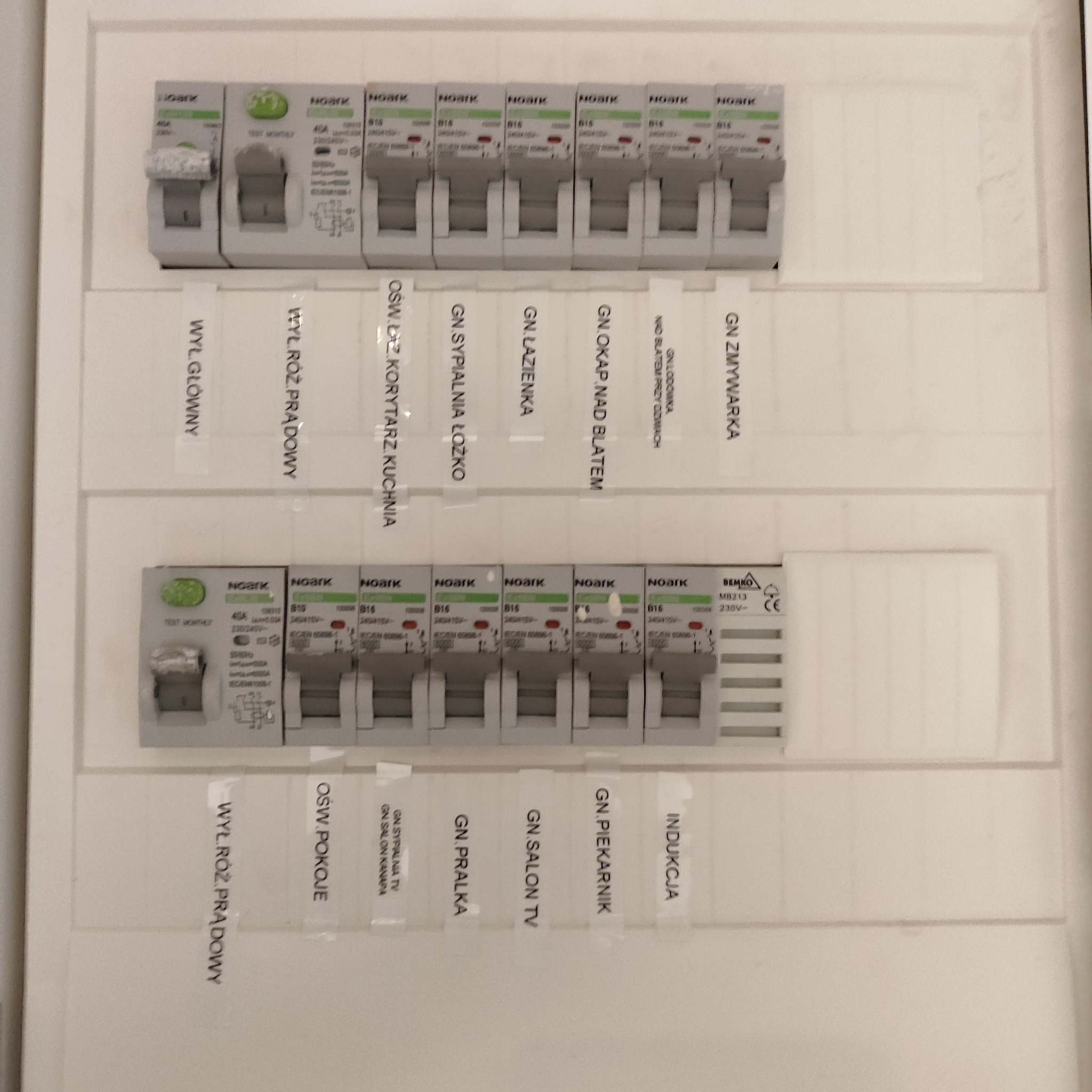 Rozdzielnica elektryczna z wyłącznikami różnicowoprądowymi i bezpiecznikami, opisana etykietami z nazwami obwodów: wyłącznik główny, wyłącznik różnicowoprądowy, oświetlenie korytarz-kuchnia...