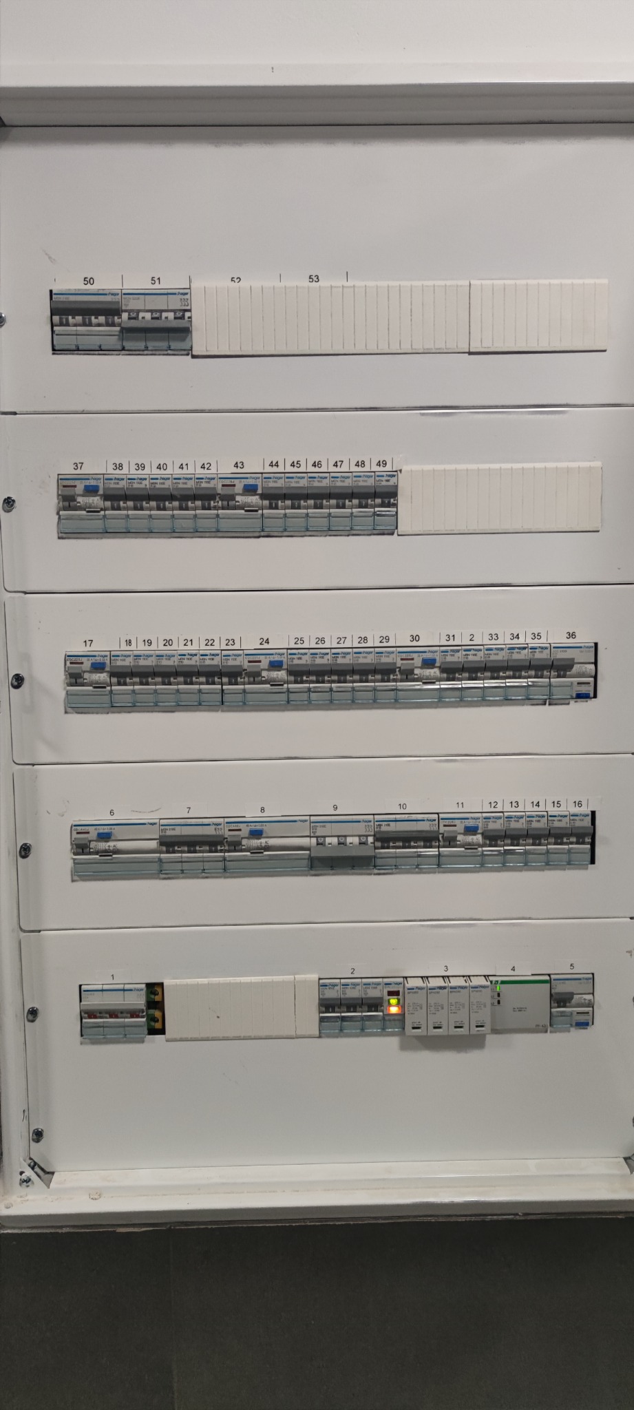 Rozdzielnica elektryczna z bezpiecznikami, kilka wyłączników w pozycji włączonej, widoczne numery poszczególnych obwodów.