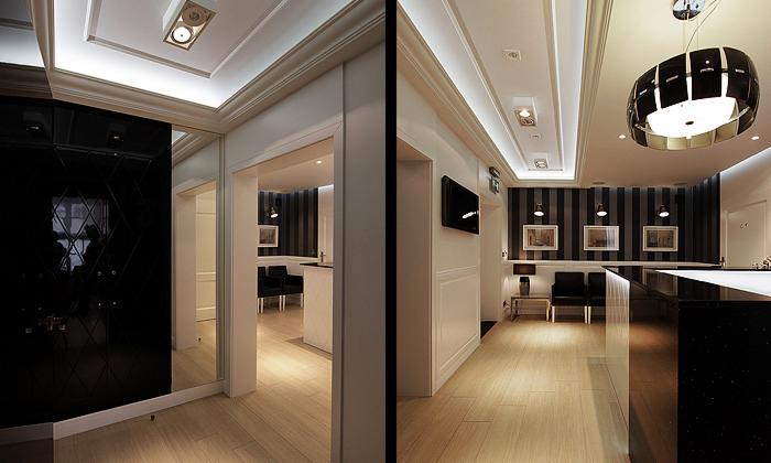 Eleganckie wnętrze biura z czarną recepcją, pasami na ścianie i nowoczesnym oświetleniem, widok z perspektywy wejścia na jasną, drewnianą podłogę.