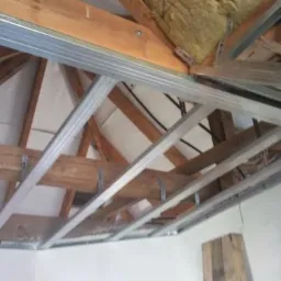 Stelaż z metalowych profili podwieszony do drewnianej konstrukcji dachu, przygotowany do montażu okładziny.