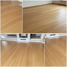 Jasna, drewniana podłoga ułożona w jodełkę francuską, widok na fragment salonu z kominkiem, ujęcie z niskiej perspektywy.