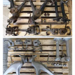 Elementy zawieszenia samochodowego przed i po czyszczeniu, ułożone na drewnianej palecie. Górna część zardzewiała, dolna pokryta srebrną powłoką.