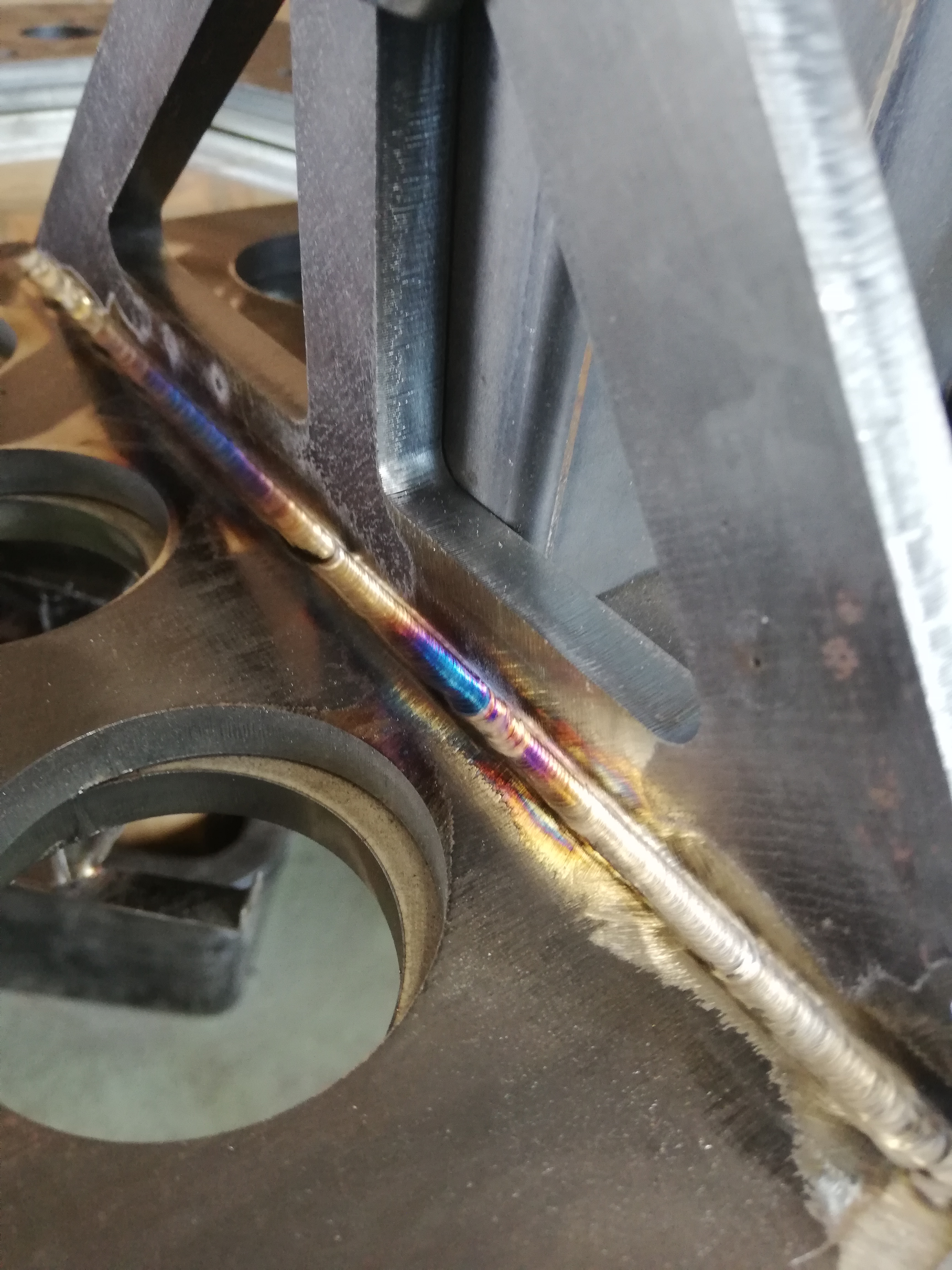 Spoina na metalowej konstrukcji z widocznymi kolorami tęczy świadczącymi o wysokiej temperaturze, wykonana metodą TIG.