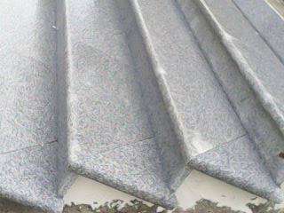 Fragment wykończonego tarasu lub schodów zewnętrznych z szarej, nieregularnej kamiennej nawierzchni, widok z góry pod kątem.