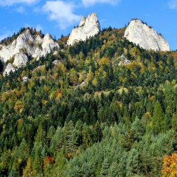 Feniks Tour Agnieszka Kozyra - Panoramiczny widok na górski szczyt z wapiennymi skałami i lasem mieszanym w jesiennej kolorystyce, błękitne niebo z chmurami w tle.