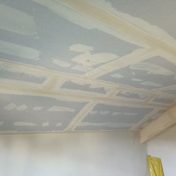 Remonty i wykończenia Ta-bud - Sufit z płyt kartonowo-gipsowych w trakcie montażu, z widocznymi łączeniami i śladami szpachlowania, instalacja elektryczna wystająca z sufitu, realizacja w Krosno.