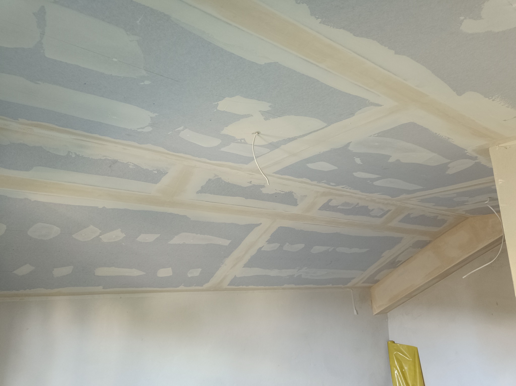 Sufit z płyt kartonowo-gipsowych w trakcie montażu, z widocznymi łączeniami i śladami szpachlowania, instalacja elektryczna wystająca z sufitu, realizacja w Krosno.