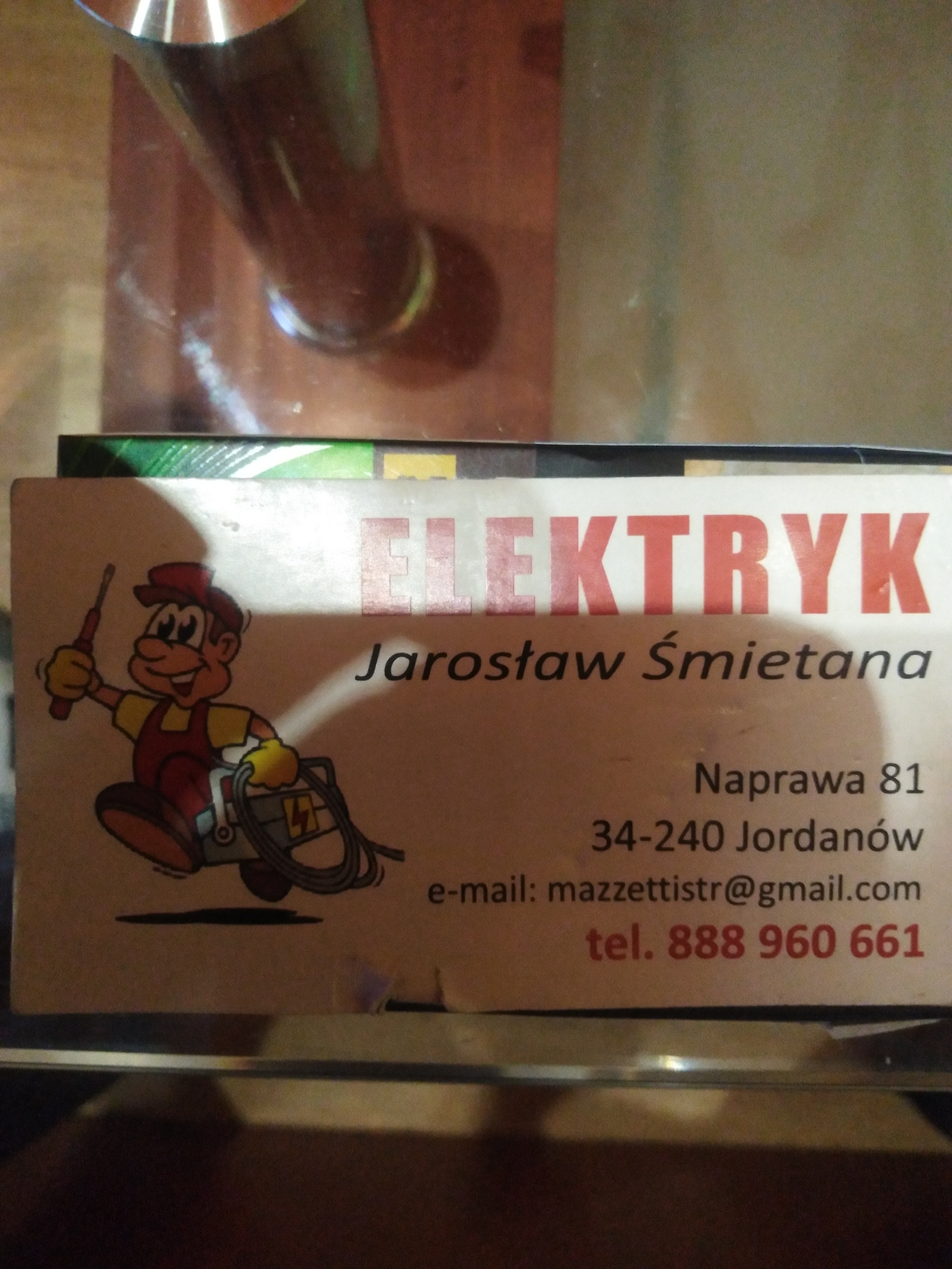 Wizytówka z kreskówkowym elektrykiem trzymającym śrubokręt i skrzynkę z kablem, dane kontaktowe: imię, nazwisko, adres, e-mail, numer telefonu.