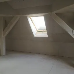 Poddasze z oknem dachowym, ściany wyłożone płytami gipsowo-kartonowymi na konstrukcji wsporczej, widoczne ślady po szpachlowaniu.