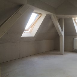 SUPRA PRZEDSIĘBIORSTWO BUDOWLANE - Poddasze w trakcie wykańczania: zamontowane płyty kartonowo-gipsowe, widoczne drewniane okna dachowe i elementy konstrukcyjne, przygotowane do dalszych prac wykończeniowych.