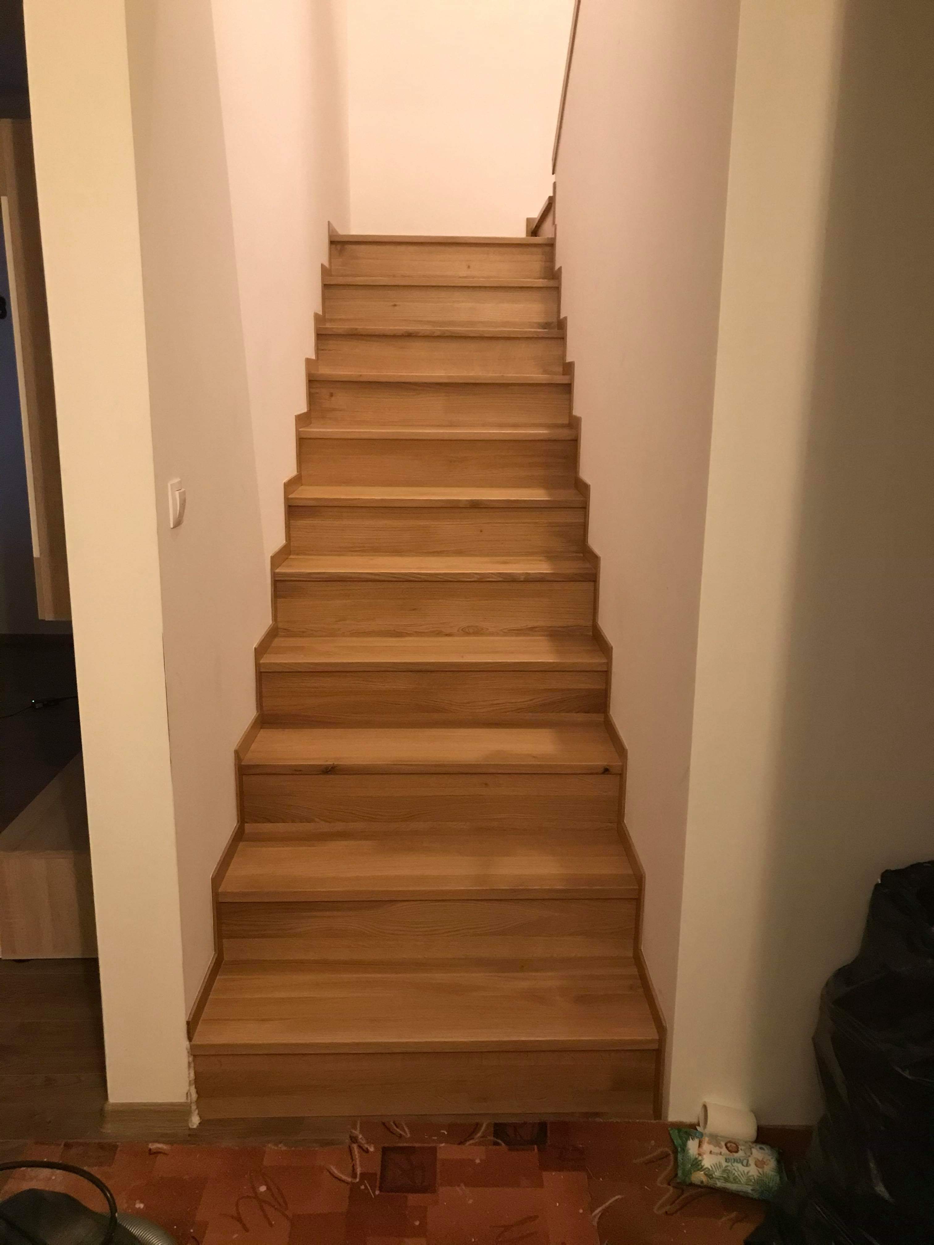 Proste, drewniane schody bez poręczy, widok z dołu na górę, z widocznym fragmentem podłogi w trakcie remontu i workiem na śmieci.