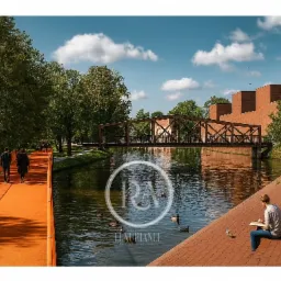 Nowoczesna architektura krajobrazu: pomarańczowa ścieżka wzdłuż kanału, drewniany most, ceglany budynek i osoba rysująca na brzegu. Słoneczny dzień.