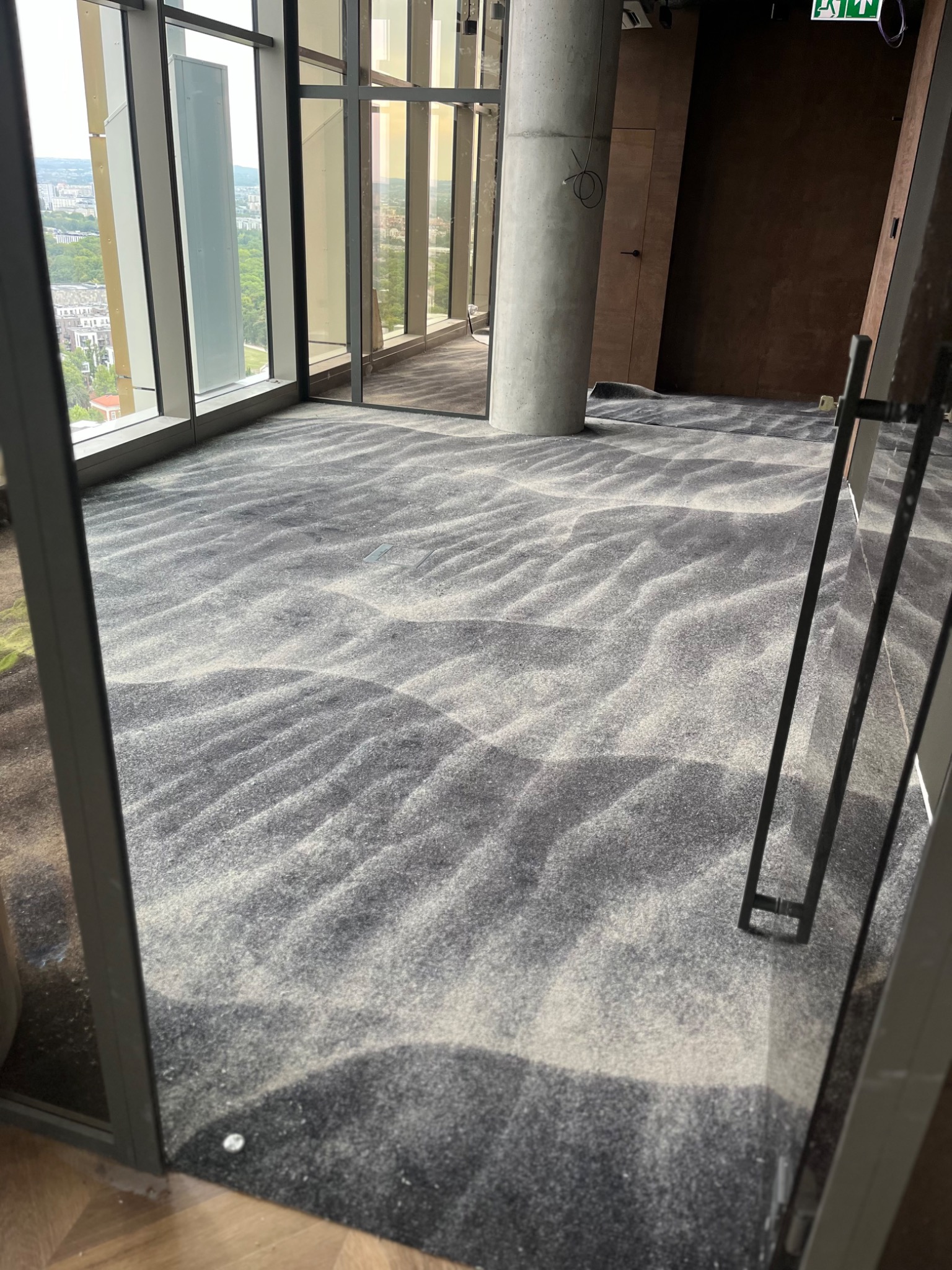 Wzorzysta, szaro-biała podłoga w nowoczesnym biurze z widokiem na miasto przez okna od podłogi do sufitu. Elementy konstrukcyjne w tle.