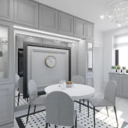 Jasna, szara kuchnia z okrągłym stołem, czterema krzesłami, kryształowym żyrandolem i zabudową meblową z przeszklonymi witrynami, widok na zegar w ramie.