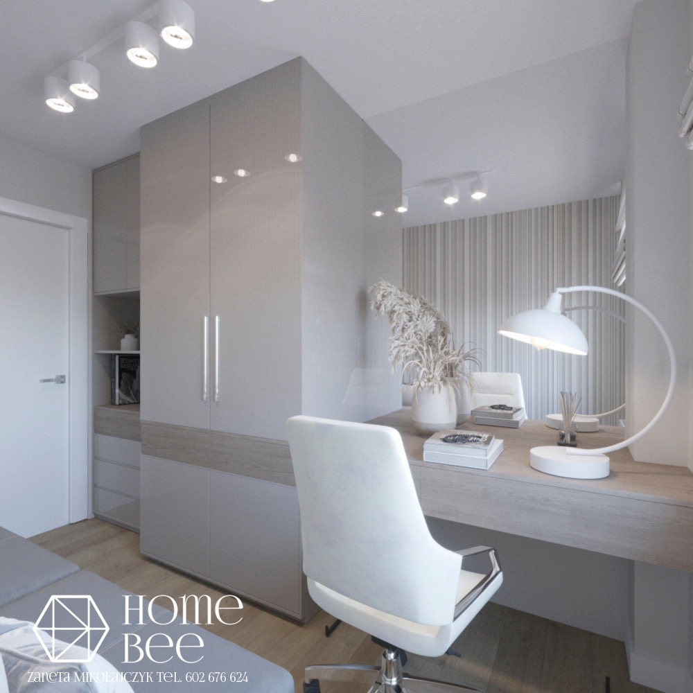 Nowoczesne biuro domowe w odcieniach szarości, z minimalistyczną szafą w zabudowie, biurkiem z dekoracjami, białym krzesłem obrotowym i lampą biurkową. Widoczny fragment sofy z logo firmy Home Bee.