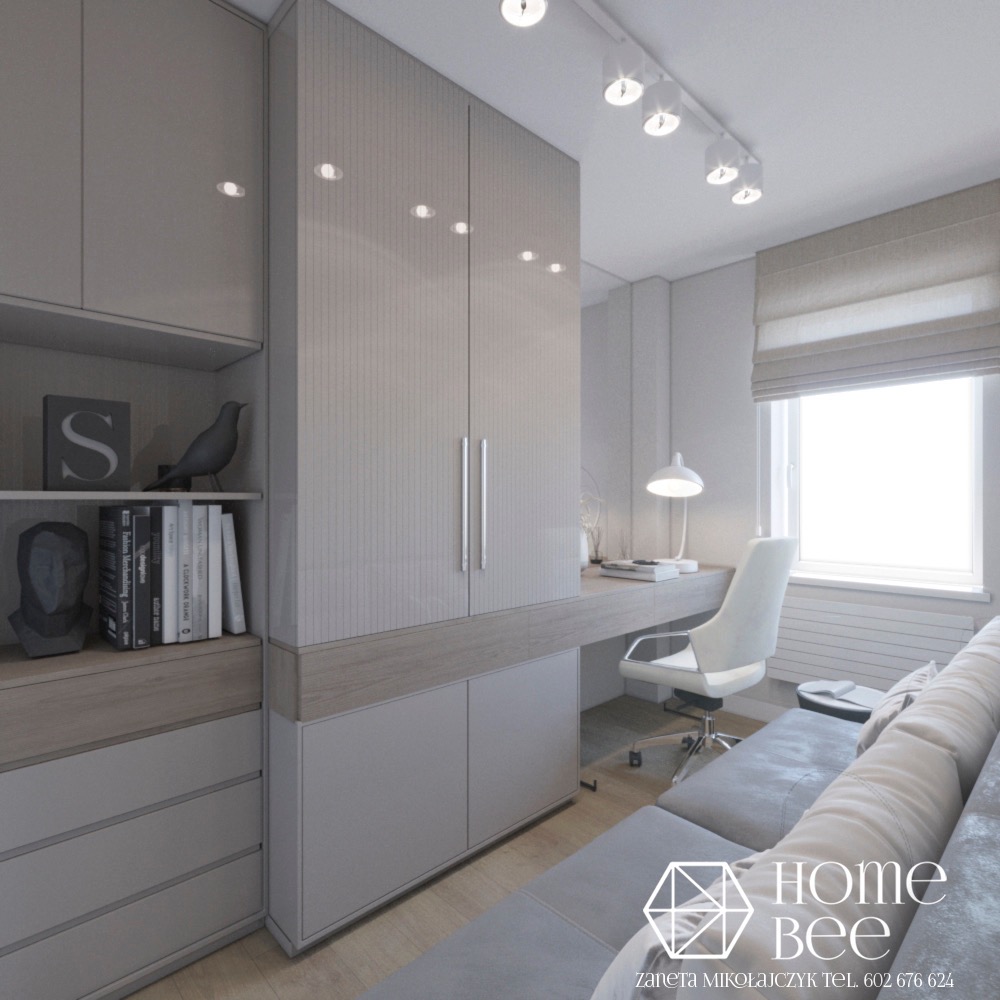 Jasnoszara szafa z pionowymi żłobieniami i półkami z dekoracjami, biurko z krzesłem i lampką, szara sofa w tle, oświetlenie punktowe na suficie, logo firmy w prawym dolnym rogu.